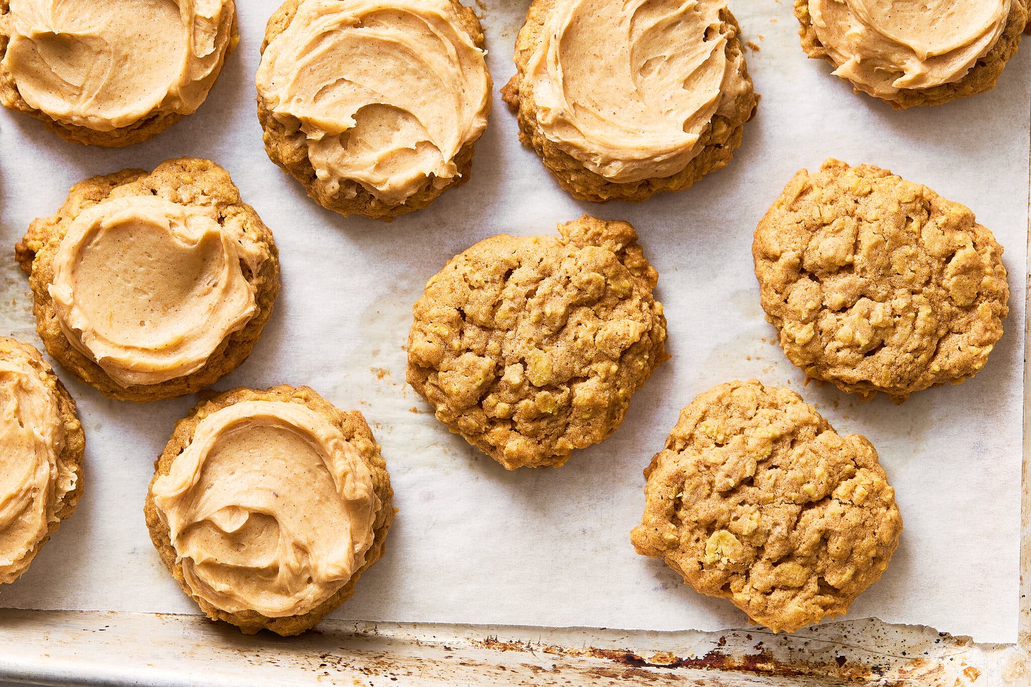 An overhead image of pumpkin oatmeal cookies, with several topped with pumpkin spice frosting.