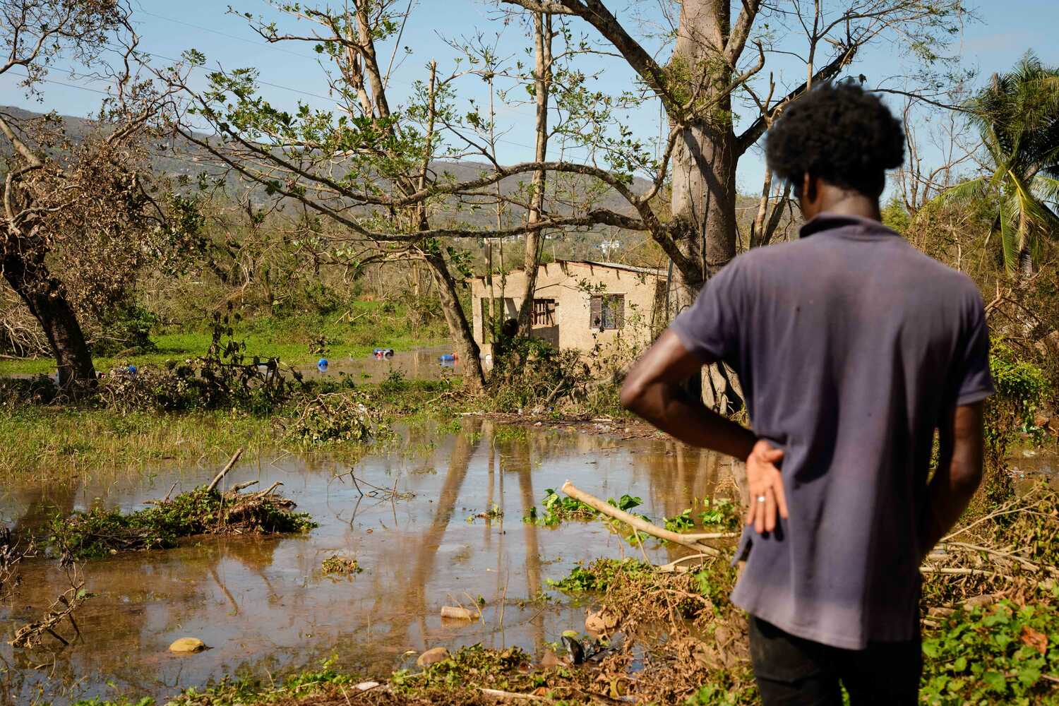 A man looking at flooding, with a building beyond it.