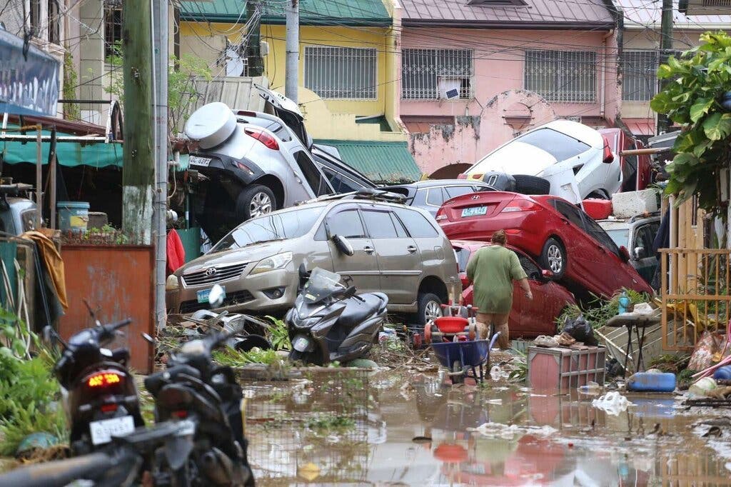 A pileup of cars on a flooded street strewed with debris.