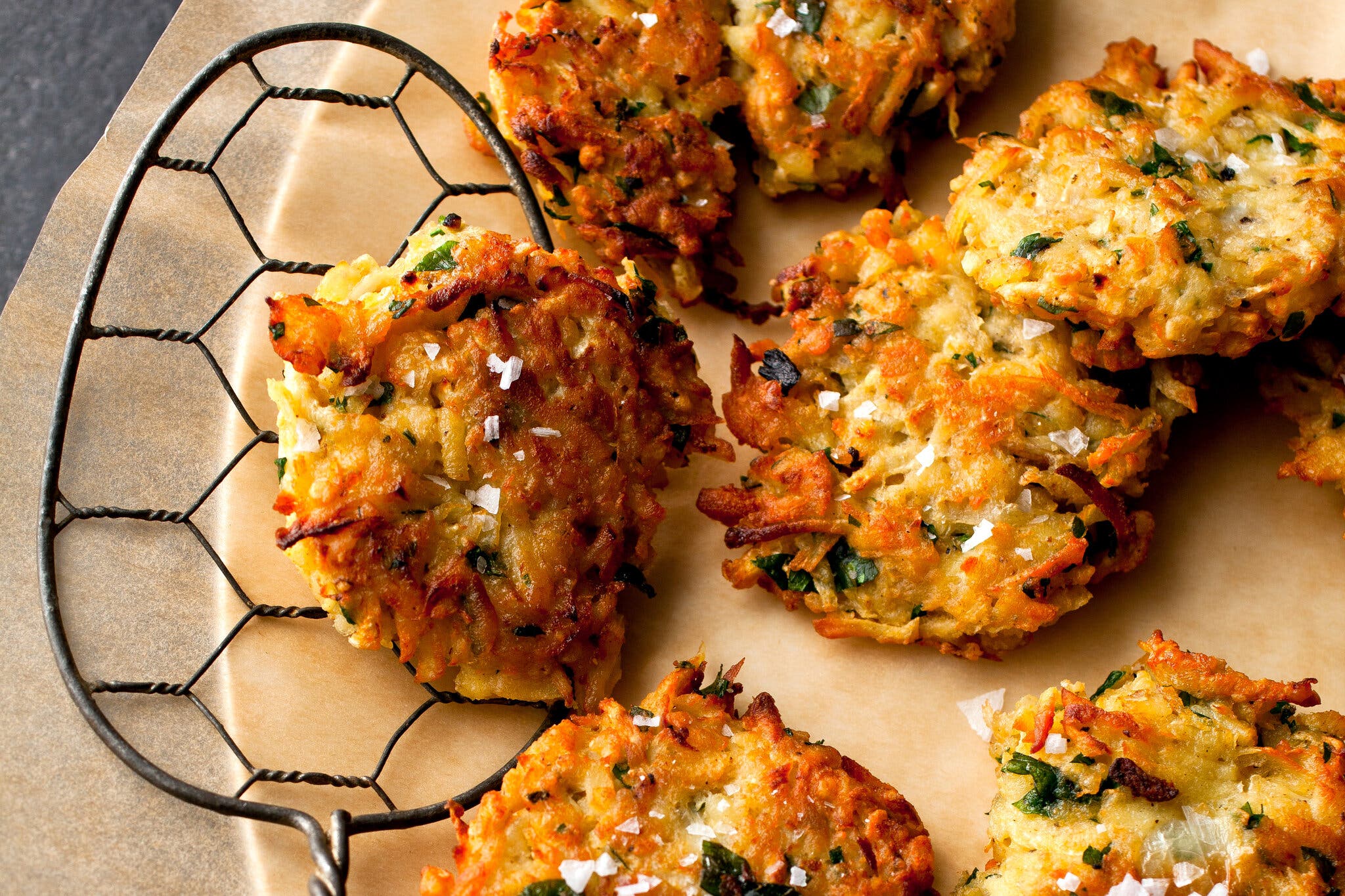 A platter of celery root-parsnip latkes on a parchment-lined platter with a spatula.