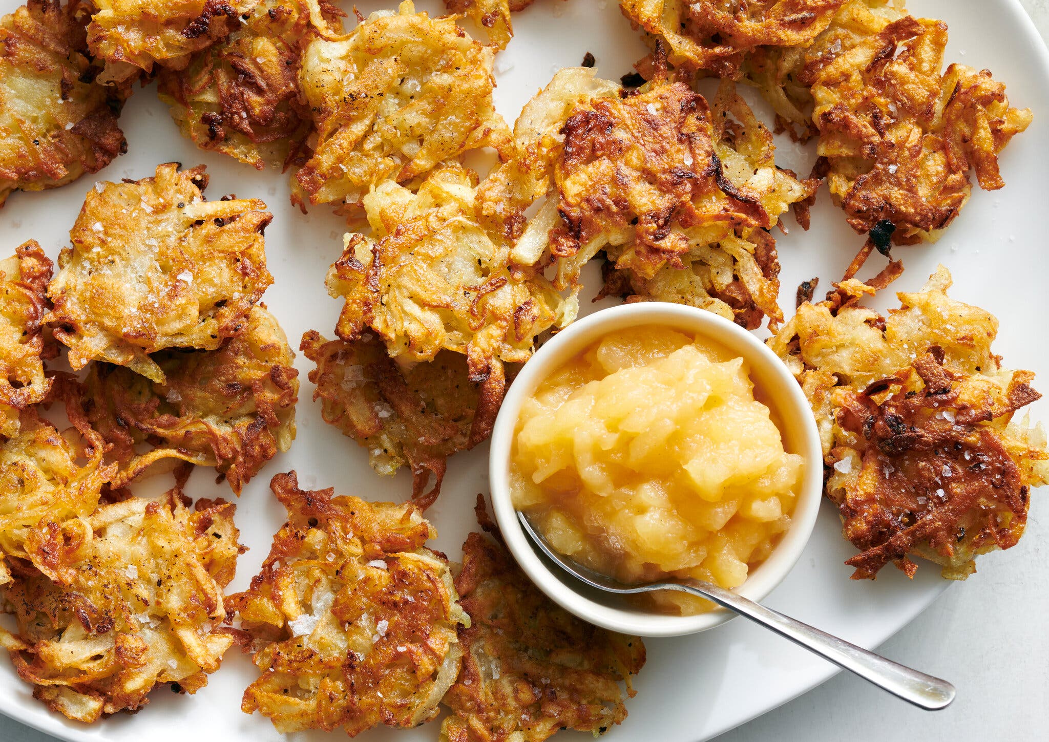 A platter of vegan latkes with a small dish of applesauce alongside.
