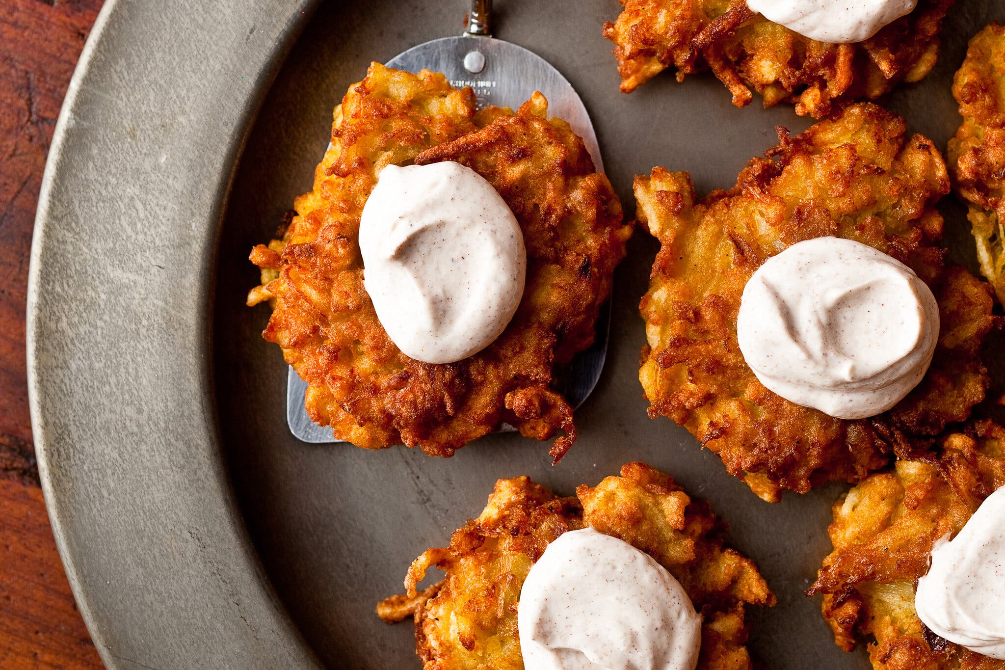 A platter with several apple-potato latkes topped with cinnamon sour cream.