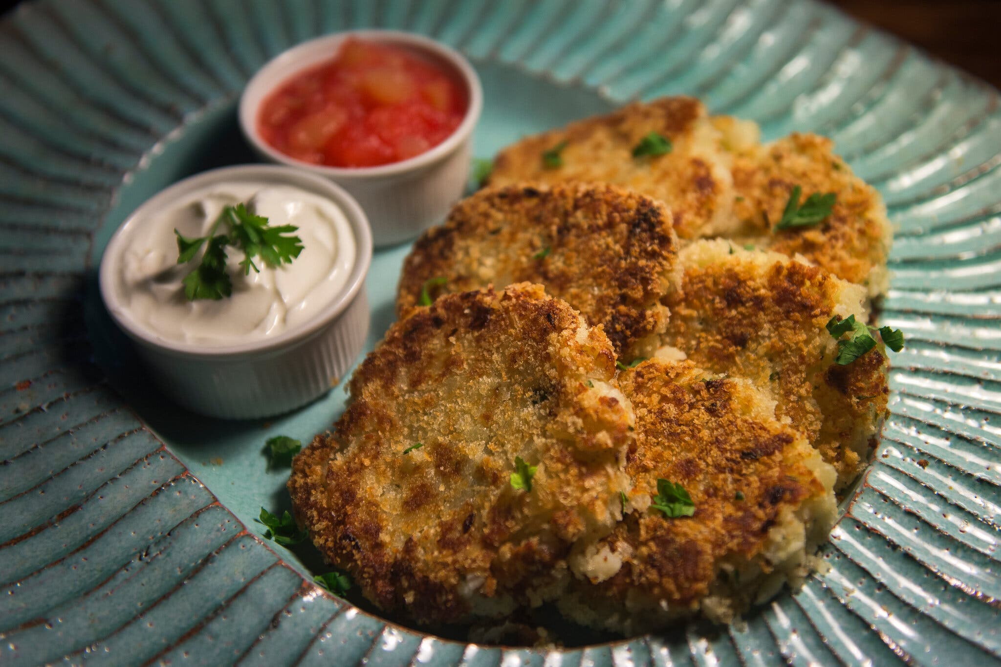 A plate with several potato pancakes, with sour cream and compote alongside.