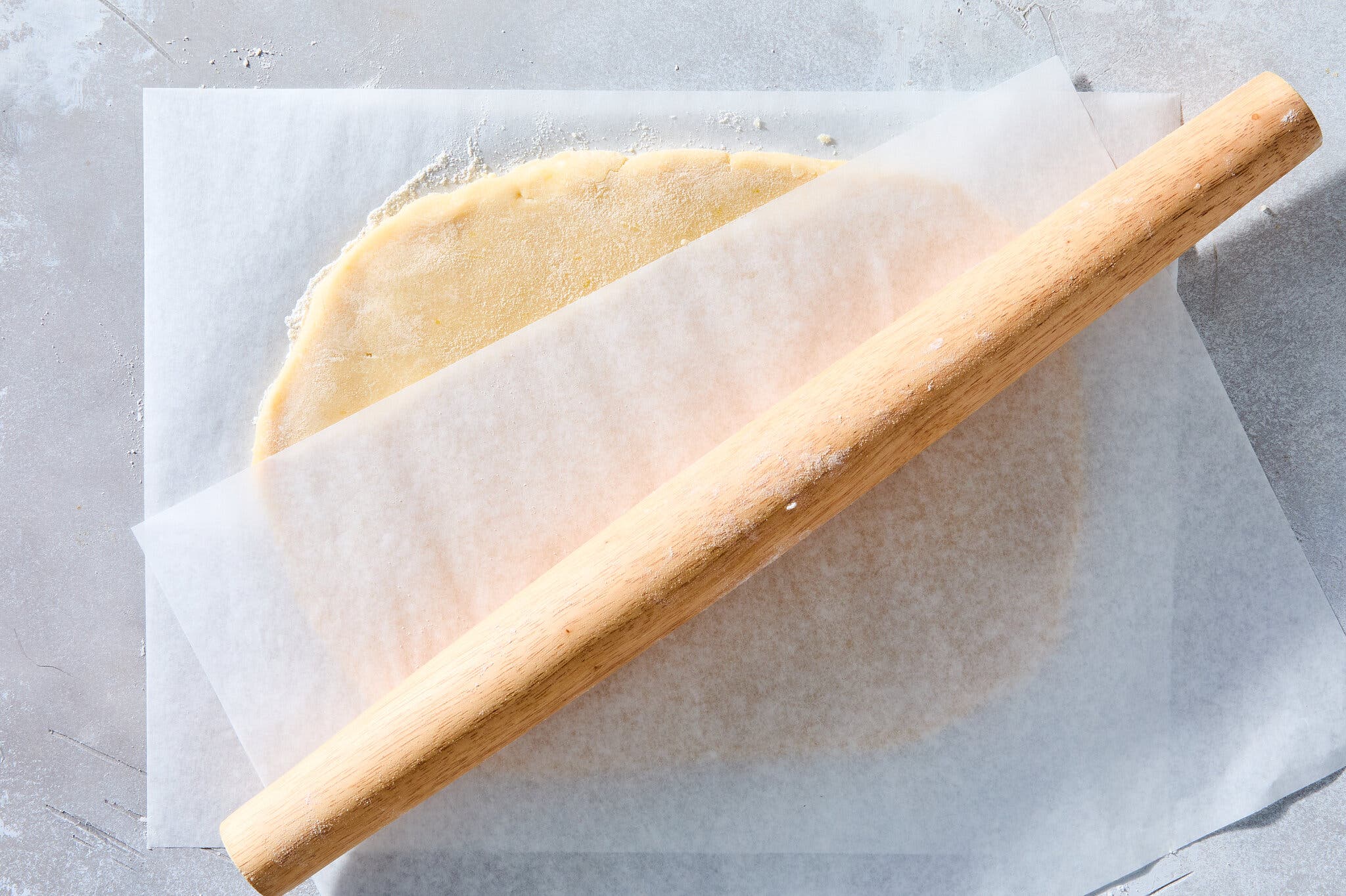 An overhead image of flat dough rolled between two pieces of parchment.