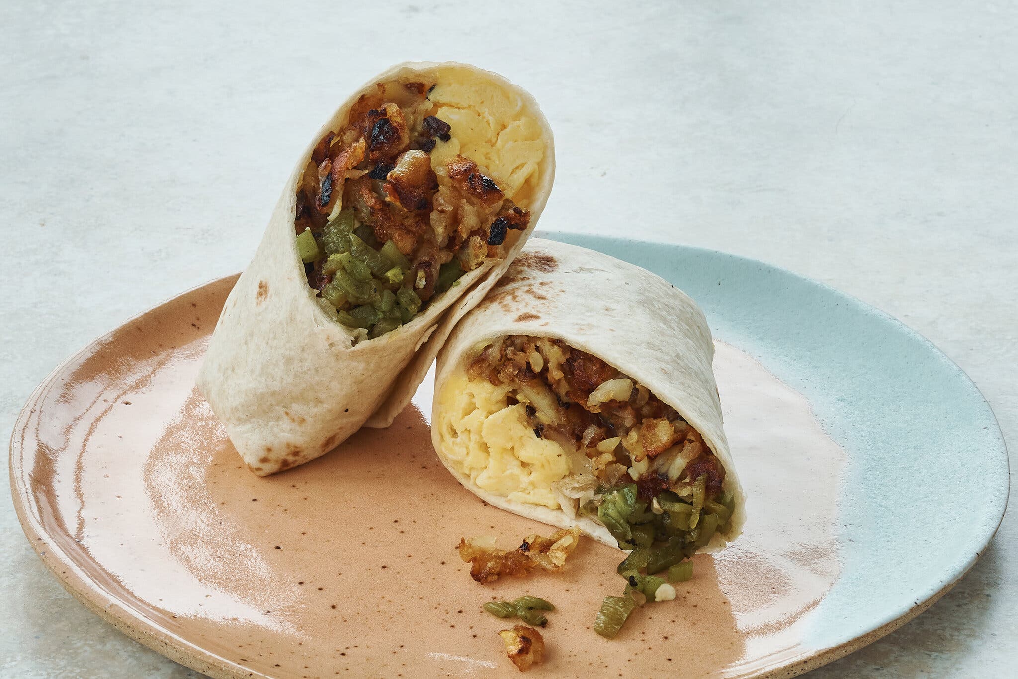 A cut-open burrito with eggs, potatoes and green chiles inside.
