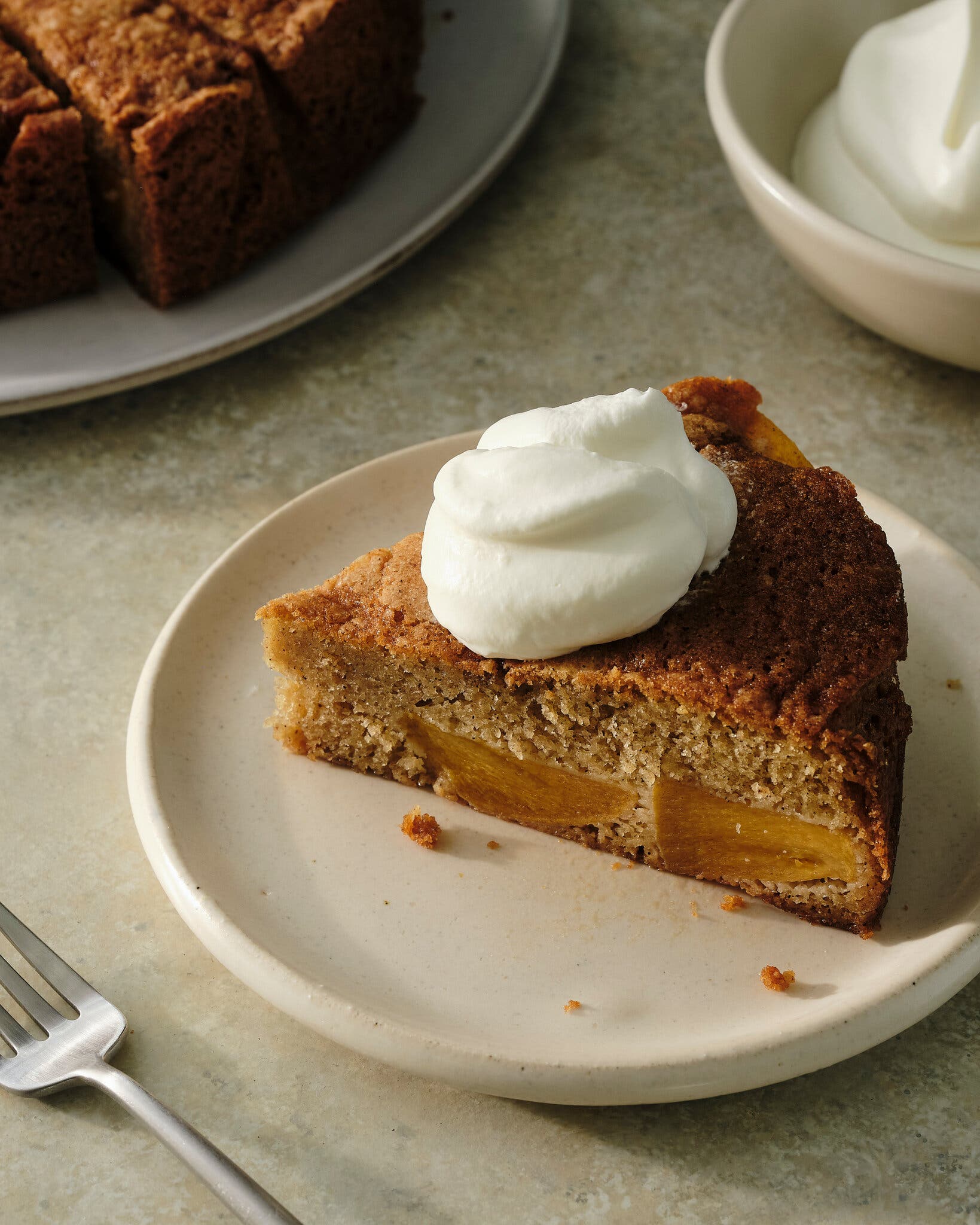 A side image of a plated slice of persimmon cake topped with whipped cream.